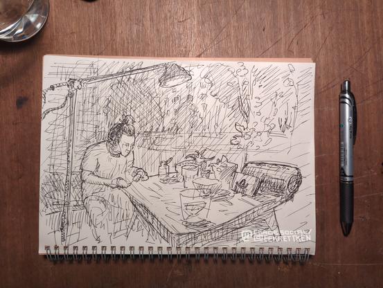 A person is painting their Nils on a table with stuff on it (glasses, plant pots, speaker, phone, etc). A lamp is above them. Different plants, trees, and a house are indicated darker in the background.
