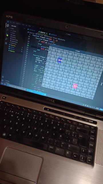 Laptop corriendo editor de código y ventana de videojuego básica similar al juego Battle City