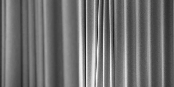 A 2×1 aspect ratio, back and white, photograph of monochrome curtains. A horizontally alternating light and dark pattern, with grain (aka sensor noise).

The combination of grain, black and white and the aspect ratio give the photograph a cinematic feel.