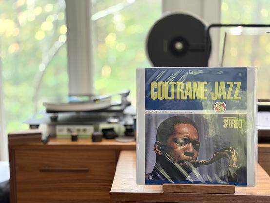 John Coltrane - Coltrane Jazz LP cover.

Top 1/3 the title, bottom third a picture of Coltrane playing his sax.

The black LP plays on a Rega NAIA turntable to the left.