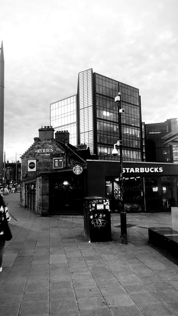Looking past 1860s Ryries pub to a tall, glass and steel modern office block, late night but just after midsummer, so still not dark