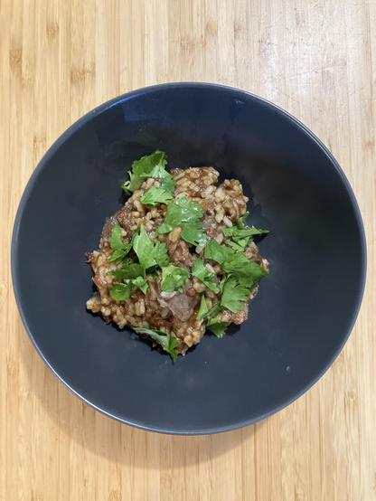 Tomato-based lamb and rice stew topped with cilantro.