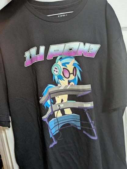 A T-shirt featuring DJ PON3 from the show My Little Pony Friendship is magic with vaporwave-like blue and purple text above the character DJing.