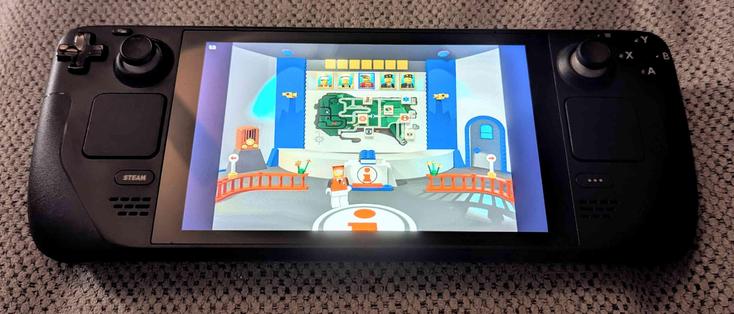 A photo of a Steam Deck laying on a couch, with the screen displaying Lego Island being played on it.  mainly the opening map screen with the character selection menu up top