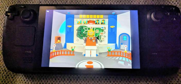 A photo of a Steam Deck laying on a couch, with the screen displaying Lego Island being played on it.  This time the camera is back on the map screen with the guide minifig front and center, explaining something to the player.