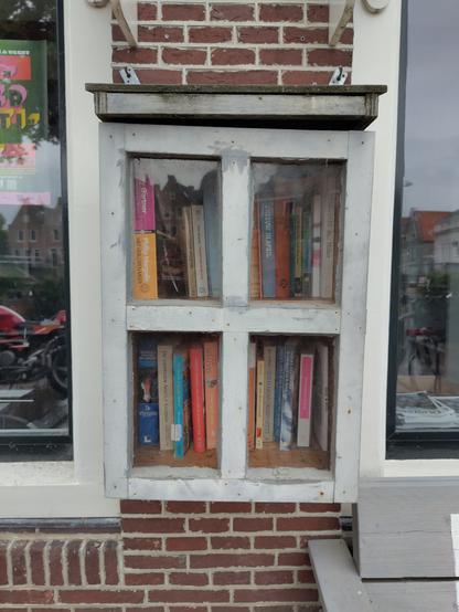 Kastje met twee boekenplanken bevestigd aan de gevel van een woning