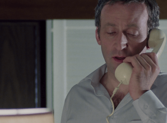 ChatGPT describes the image as "The image depicts a man with a focused and serious expression, holding a beige landline telephone receiver to his ear. He wears a light-colored shirt, slightly open at the collar, and appears to be indoors, possibly in a domestic setting, with white siding visible in the background. The setting suggests a moment of intense communication, likely linked to a plot involving intrigue, investigation, or personal conflict. The subdued lighting and his concentrated demeanor imply that the conversation may involve sensitive or critical information. The scene captures a private yet tense moment, typical of suspenseful narratives."

BotOfDarkness, version 2.0.23.