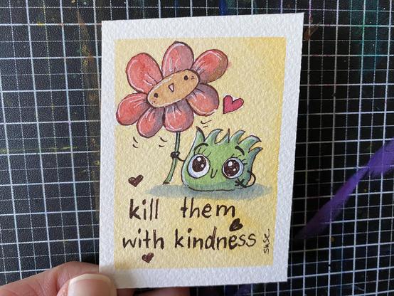 Strüppi, die sehr niedlich guckt und eine große, rote Blume hält, die ebenfalls lächelt. Datunter der Spruch: "kill them with kindness"