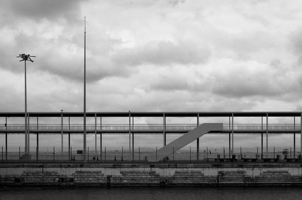 BW picture of an empty stairway at the Lisbon Cruise Port. In the background the atejo river, on an overcast day.