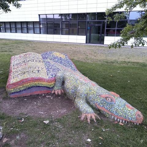 Deel van een beeldengroep met mozaiek bekleed. Uit een boek met regenboogkleuren kruipt een kleurrijke krokodil.
In het boek staan woorden als:
Hope
Freedom
Education
Love
Diversity
Respect

Dat dit geen sprookje moge blijven!