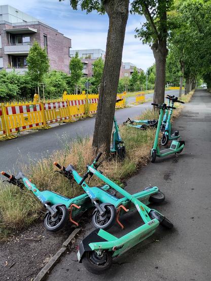 Mehrere Elektroroller der Firma Bolt stehen und liegen auf einem Fussweg in der Nähe einer Baustelle.