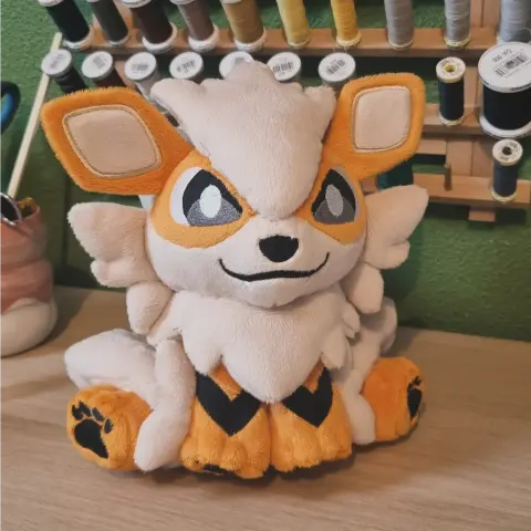 Peluche du Pokémon Arcanin en position assise. Il est très fluffy et a un petit air malicieux.