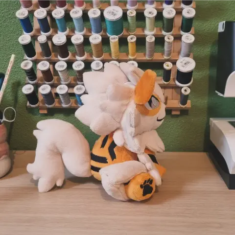 Vue de profil de la peluche qui permet de voir le fluff à l'arrière de la tête ainsi que la queue.