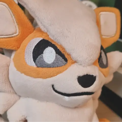 Vue rapprochée du visage de la peluche, on peut voir ses petits crocs.