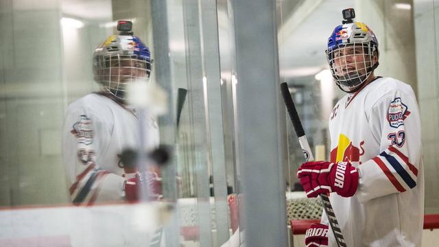 Max, in full hockey gear, stands beside the rink in Salzburg.