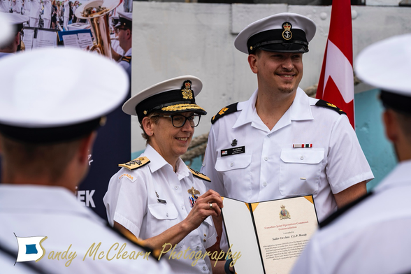 Rear-admiral presenting and award certificate to a sailor.