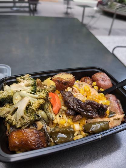 On an iron table (at 6 1/2 Av and W 55 St to be exact) is my dinner for that day: a plastic single-use lunch box with chicken, beef, potatoes, fried bananas, broccoli, carrots, and some sort of western-ish chao mein. (This is $11.50 ish.)
