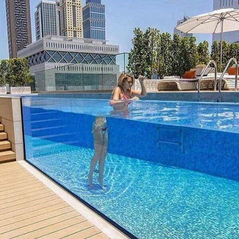 Refraction causes woman in clear-sided pool to appear as if she’s split into two halves.