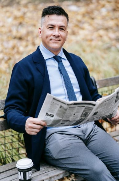 Image of man reading newspaper on park bench by Vanessa Garcia