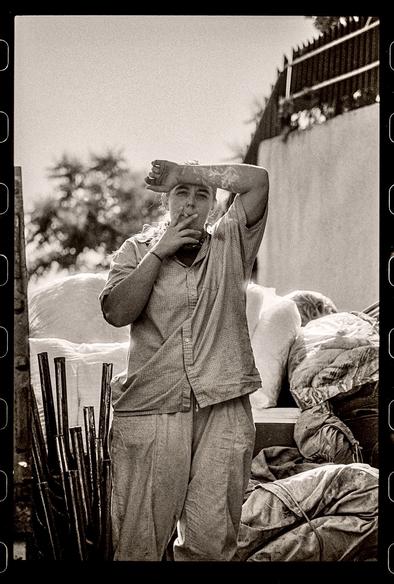 A woman looks at the camera while smoking a cigarette, surrounded by gear.