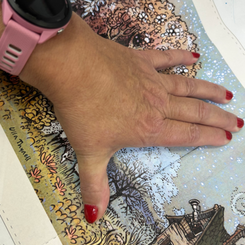 hand presses flat a color print test of an Ulla Thynell illustration for the Faraway Dreaming Art and Story Book
