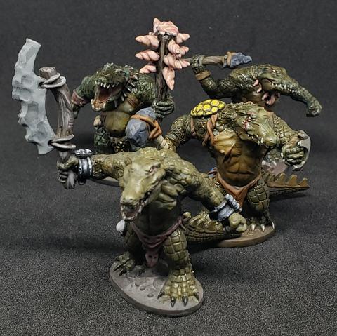 4 gatormen minis. The front most has a stone ax, the next a stone headed club and metal shield, the next a seashell studded club, and the rear most a stone tipped spear.