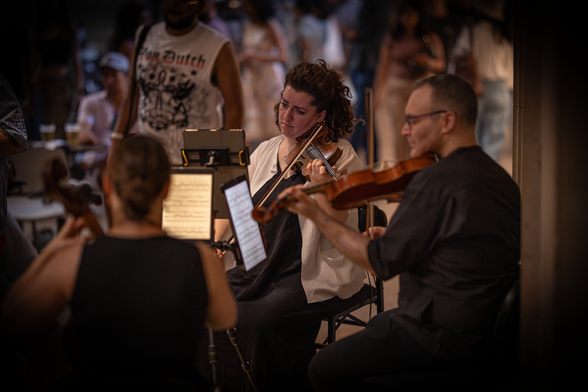 Trio Fadolin performing at the Metropolitan Museum of Art -- photo shows three musicians and a bustling atmosphere behind them