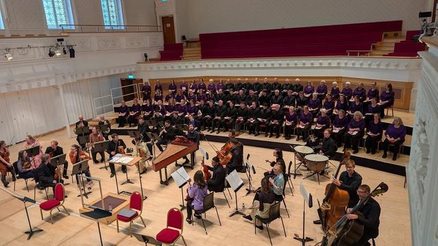 View of the stage with an orchestra and choir sitting on chairs.