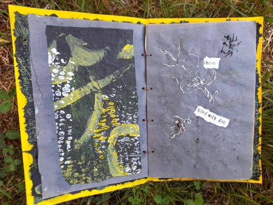 #3: double page. left: maize print in white and some yellow with yellow abstract lines painted on black tissue paper. Some yellow enhancements with intuitive embroidery. Right: white intuitive stitching with thin paper yarn and the printed words 'chaos' and 'filled' with AWE. The challenge: wild embroidery appears on the reverse and serves as inspiration for new combinations.