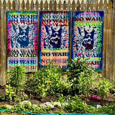 a 3-panel NO WAR! mural composed of three panels mounted on a fence.