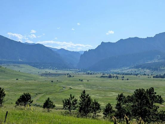 I snapped this photo of a valley beneath green covered mountains on a drive from Fort Collins to Red Rocks Colorado, June 2025.