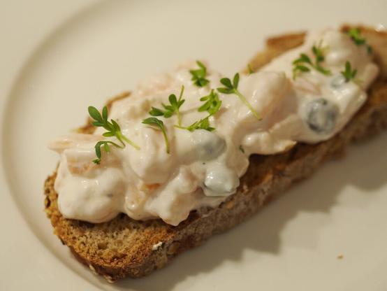 Eine Brotscheibe belegt mit der Räucherlachs-Meerrettich Creme, dekoriert mit etwas frischer Kresse