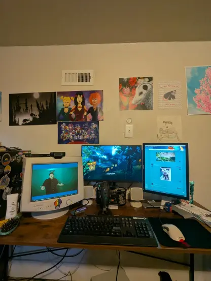 A picture of my desk setup with an old CRT on the left, a vertical 5:4 Dell display on the right, and a 1080p monitor in the center. My wall has a bunch of art from local events.