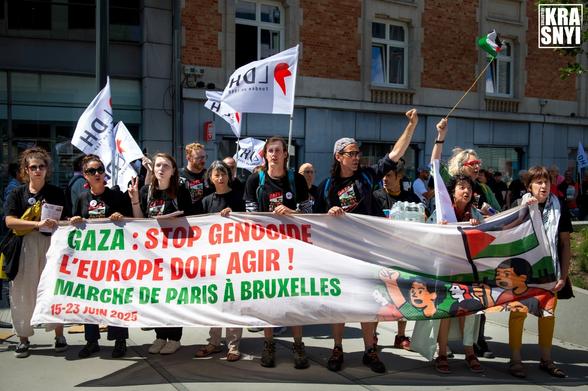 Des manifestan.te.s tendent le poing vers le ciel; devant elleux, une banderolle: "GAZA: STOP GENOCIDE, L'EUROPE DOIT AGIR ! MARCHE DE PARIS À BRUXELLES 15-23 JUIN 2025"