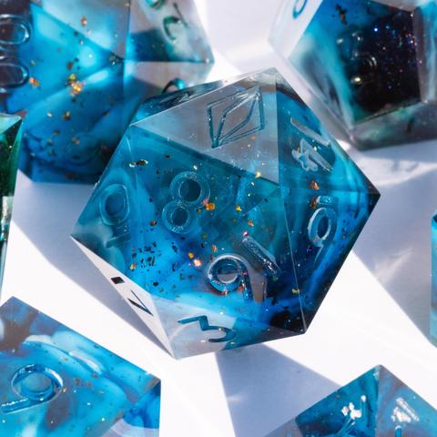 A D20 surrounded by other TTRPG dice. The dice are translucent light blue with swirls of white and green and have reflective bronze specks in them.