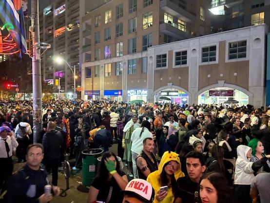 Une foule compacte, dont beaucoup de gens déguisés, de nuit dans une rue