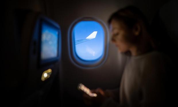 Una mujer usando su móvil en un avión. (Getty Images)