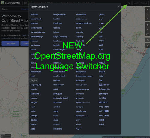 OpenStreetMap.org website home page with a green arrow pointing at the new Language Selector (i18n) icon near top right of selection bar. The language selector dialog is open with many languages displayed. Green overlay text: "New OpenStreetMap.org Language Switcher"