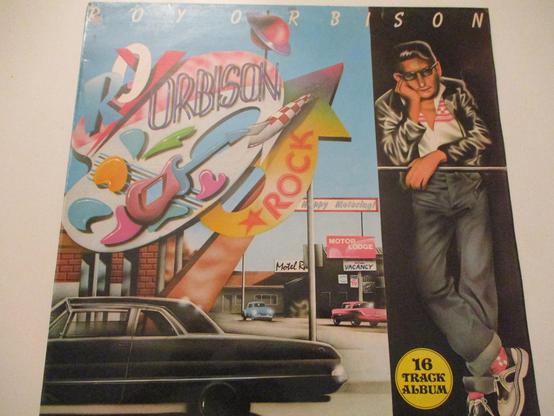 Pochette de mon 33T, pas la plus belle, mais bien colorée avec une bagnole noire brillante au premier plan, une enseigne géante avec le nom de notre vedette Roy Orbison, un motel en arrière-plan. Roy quand à lui a comme toujours le vague à l'âme dans une partie obscure à droite de l'image