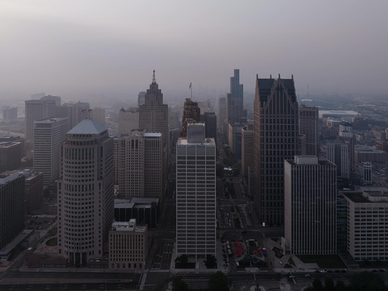 A foggy cityscape featuring a variety of tall, modern skyscrapers dominates the skyline.