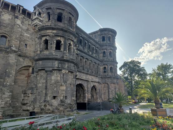 Die Außenseite der Porta Nigra (ehemaliger Eingang nach Trier)

Vor dem Stadttor stehen Dattelpalmen in Töpfen