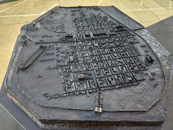 Stadtmodell des römischen Trier vor der Porta Nigra.

Die Porta Nigra ist das Stadttor unten im Bild. Darüber ist eine römische Stadt mit Häuserblöcken im Schachbrettmuster zu sehen. Links oberhalb der Porta Nigra befindet sich eine Wagenrennbahn (Circus).
Rechts oberhalb der Porta Nigra der Mars Tempel