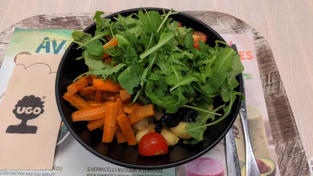 Schwarze Schüssel mit auf den ersten Blick überwiegend grüner Füllung aus Rukola, Möhren, Tomaten, schwarzen Oliven und Gnocci.