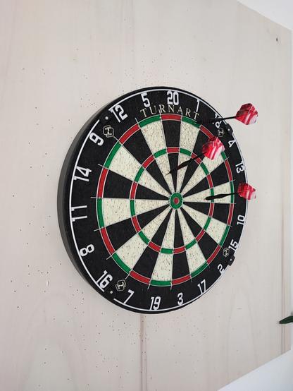 Eine Dartscheibe, wo Pfeile darin stecken.