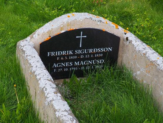 A grave with a black headstone with the names Friðrik Sigurðsson and Agnes Magnúsdóttir with their birth and death dates on it.