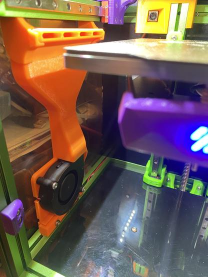 An orange 3D printed bed blower fan duct inside a green and purple Voron 0.2 printer