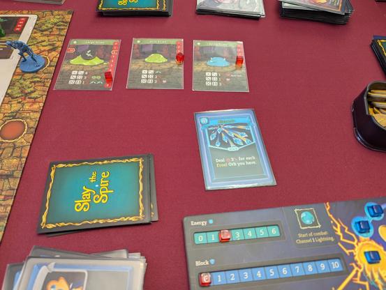 A Large Slime, Acid Slime and Spike Slime getting absolutely obliterated with a single card played in Slay the Spire: The Board Game.