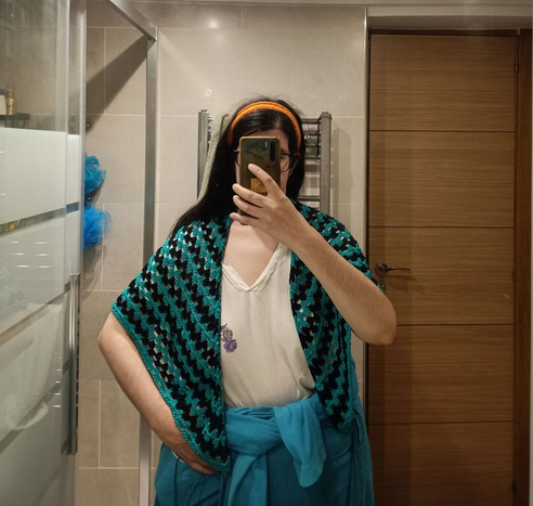 Selfi sacada en el baño, anonimizada por plantar el móvil a la altura de la cara.
Llevo Emochal como chal, sobre los hombros, tapando desde la base del cuello hasta el comienzo del codo. Los picos caen por el pecho hasta más allá de la altura del ombligo.