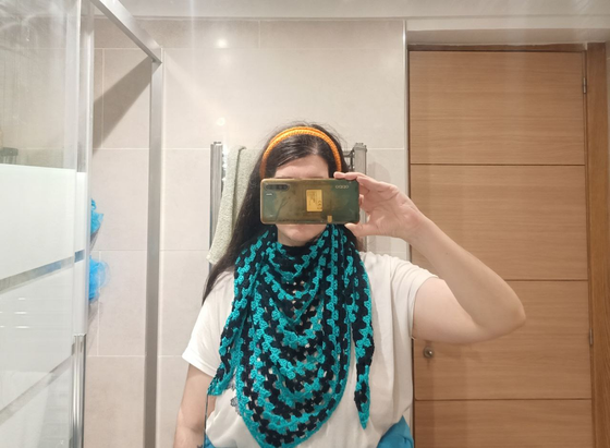 Selfi sacada en el baño, anonimizada por plantar el móvil a la altura de la cara.
Llevo Emochal como pañuelo, enrollado en torno al cuello con mucho volumen. La parte central del chal cae por el echo haciendo arrugas y el pico central queda a la altura del ombligo. Los picos laterales, después de rodear el cuello caen a los lados hasta la altura del pecho y un poco más abajo.