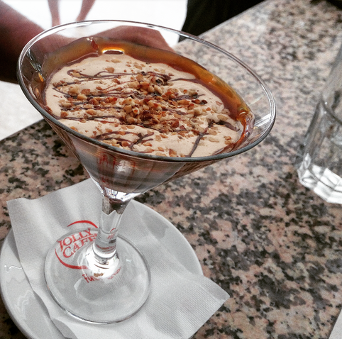 Dessert in martini glass with nuts and chocolate drizzle, on a napkin with logo.